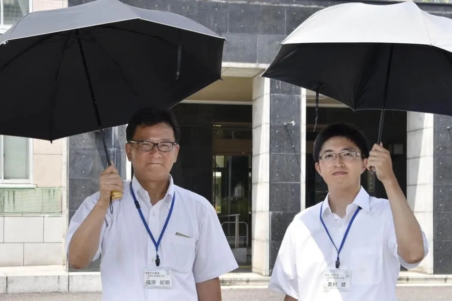 No Japão sufocante, os homens recorrem a guarda-sóis para se refrescarem